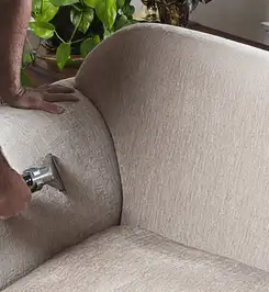 Professional upholstery cleaner deep-cleaning a fabric sofa with a handheld extraction tool and hose Stockton, CA.